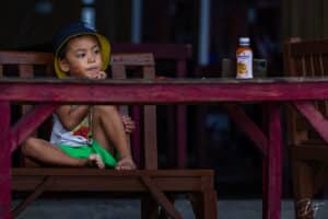 Portrait artistique d’un enfant avec une trace de rouge à lèvres en forme de bisou sur la joue, par BFO Photographie à Nouméa.