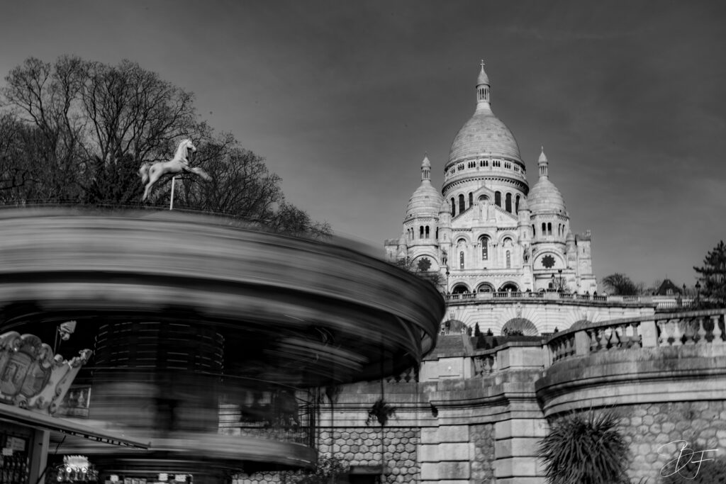 Manège en mouvement au pied de la basilique du Sacré-Cœur à Montmartre, photo en noir et blanc par BFO Photographie