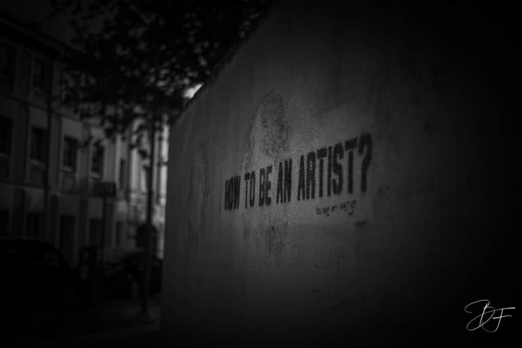 Mur urbain sombre portant l'inscription « How to be an artist ? », photo de rue en noir et blanc par BFO Photographie