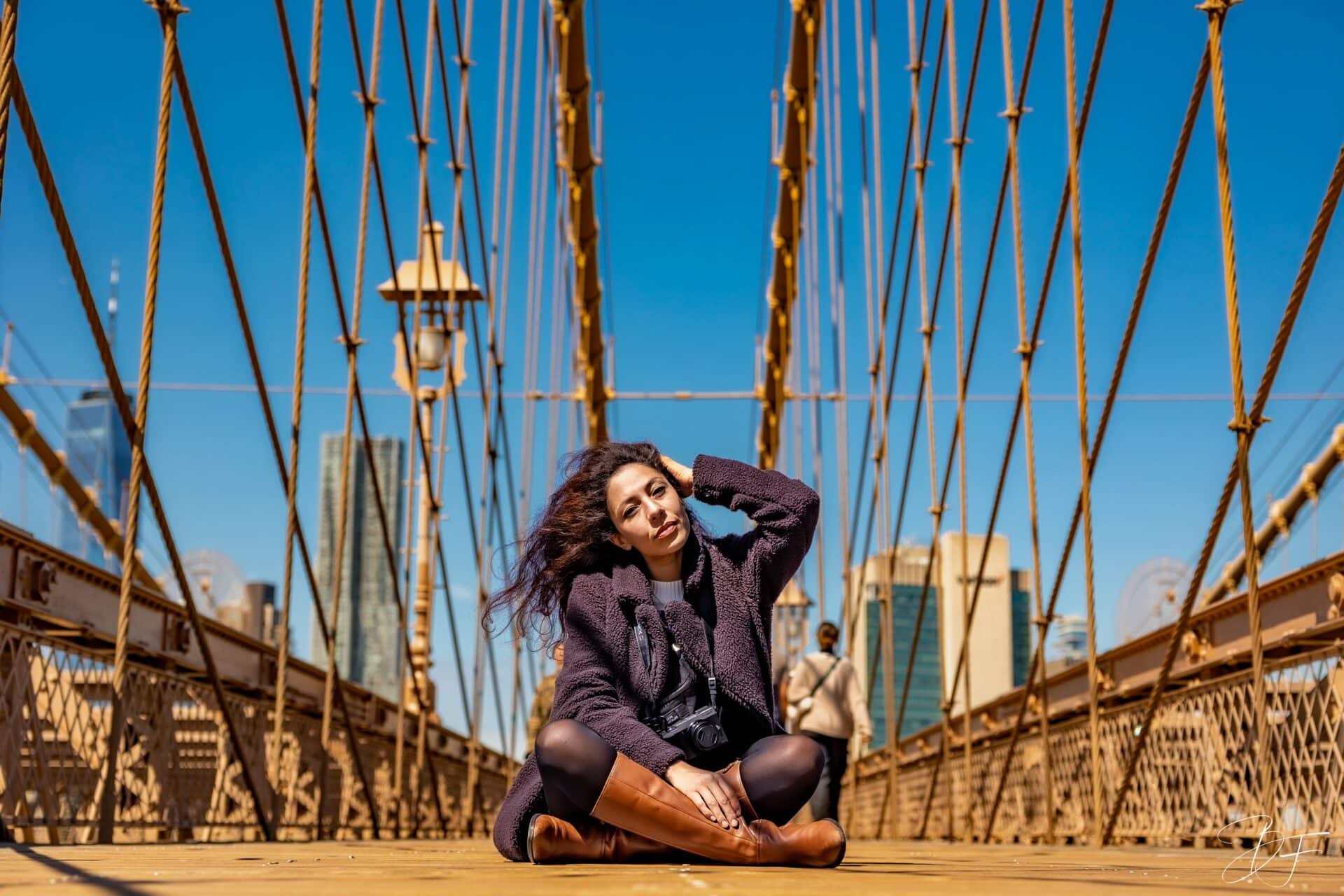Jeune femme assise au centre du pont de Brooklyn, entourée des haubans, portrait de voyage à New York par BFO Photographie