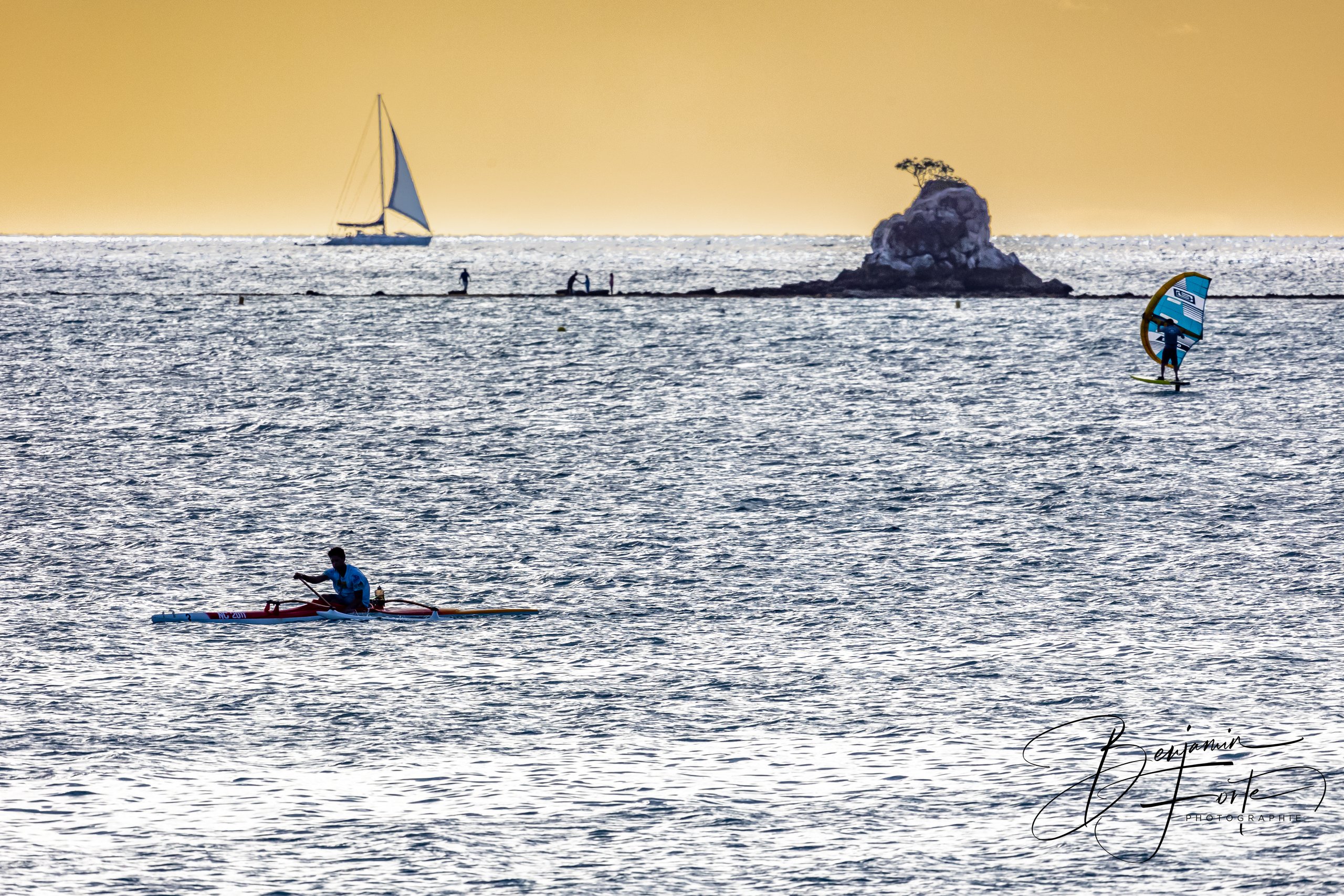 Voilier, wingfoil et kayak autour du Rocher à la Voile sur le lagon de Nouméa, en contre-jour doré, par BFO Photographie