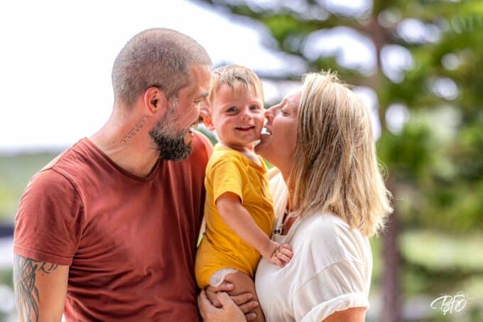 Parents embrassant leur jeune enfant sur les joues, séance photo famille pleine de tendresse par BFO Photographie