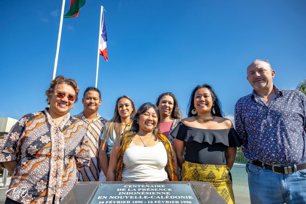 Le bureau de l'association Kumpulan Anak Niaoulis PAÏTA et le maire de Païta, Antoine Romain, souriants devant la stèle du centenaire de la présence indonésienne en Nouvelle-Calédonie, à la mairie de Païta, par BFO Photographie